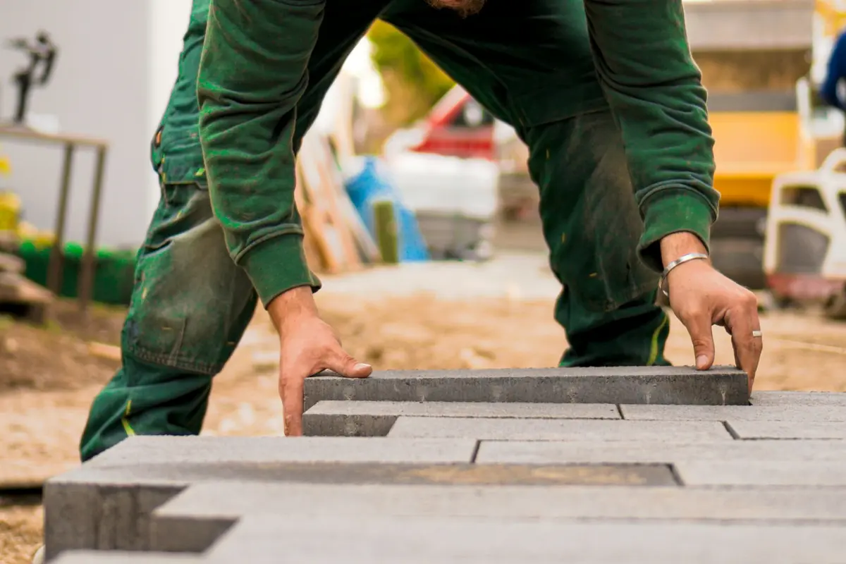 Installer setting modern grey linear pavers on a residential project